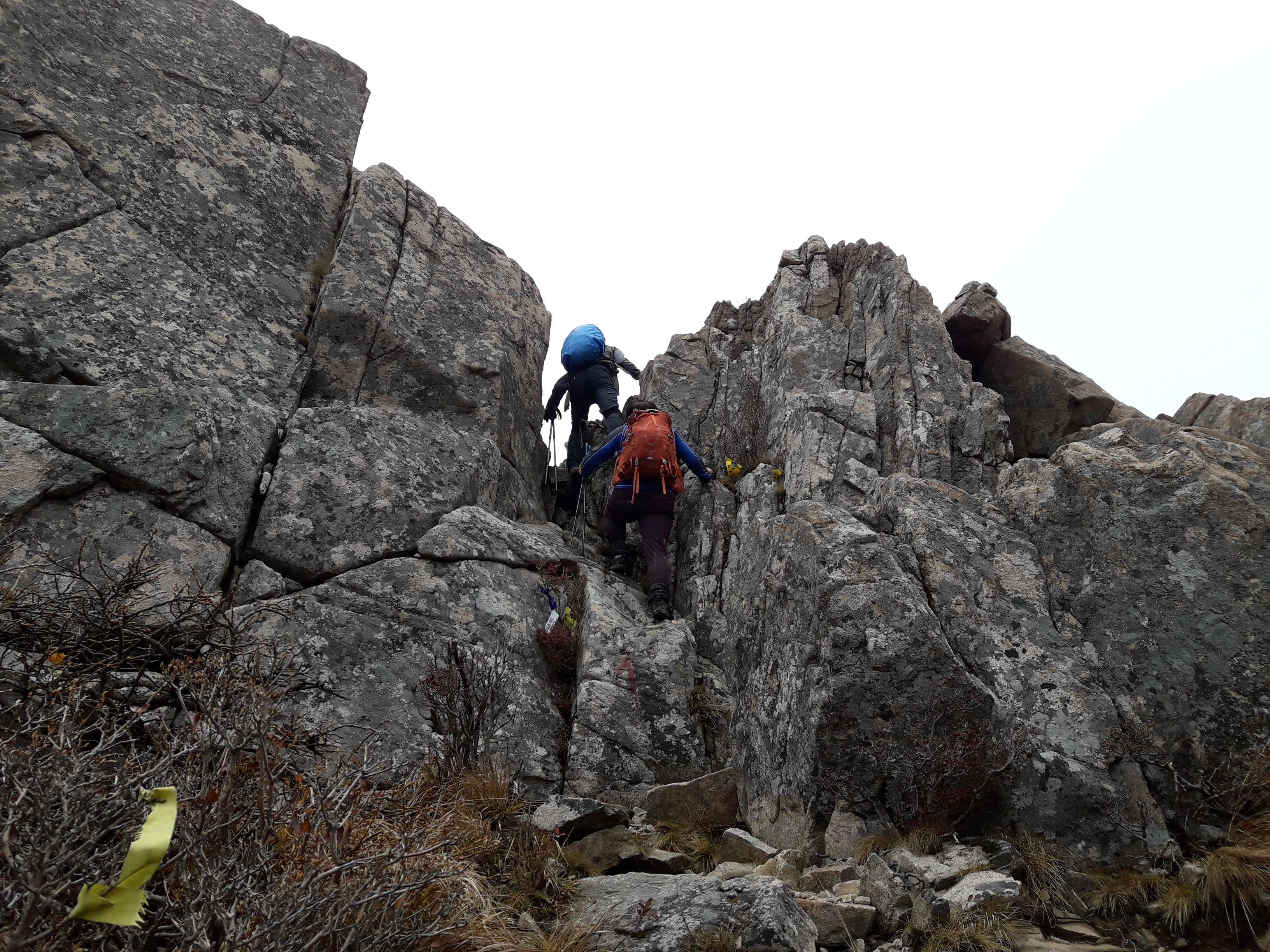 Two people climbing a rocky mountain.