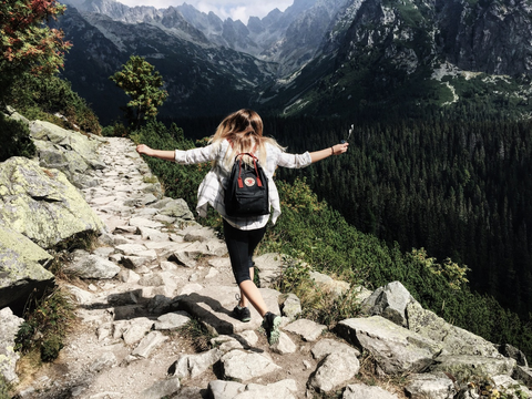 A Backpacking Woman Walking on Rocks