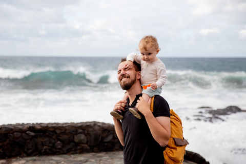 A Man Wearing a Backpack and Carrying a Kid on his Shoulder
