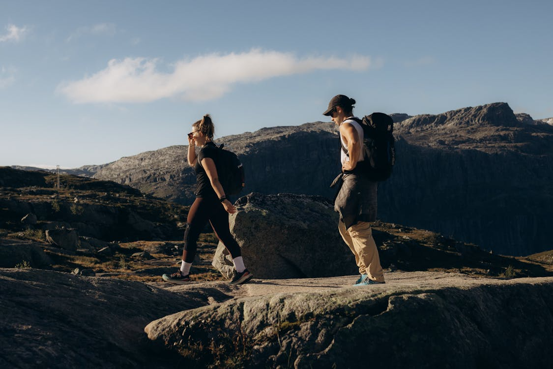 Two hikers walking across rocky terrain with backpacks.