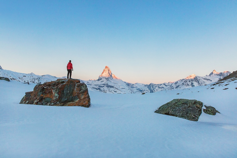 A backpacker standing on a rock in snow