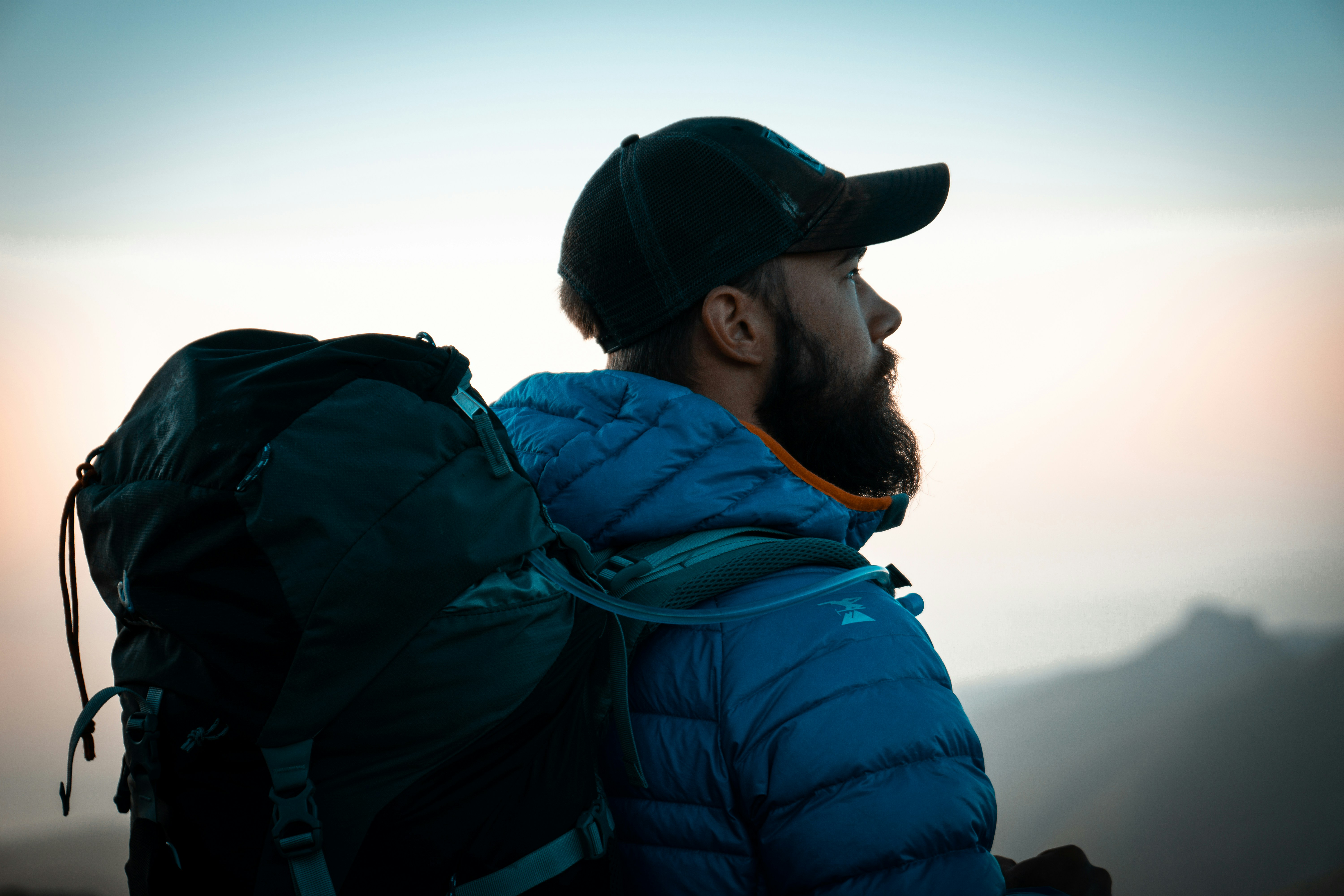 Hiker wearing a backpack and outdoor jacket while overlooking a mountain landscape during a hiking trip.