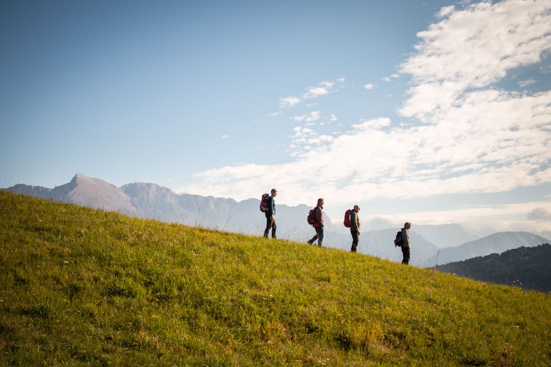 Group of hikers walking with backpacks on a hillside.
