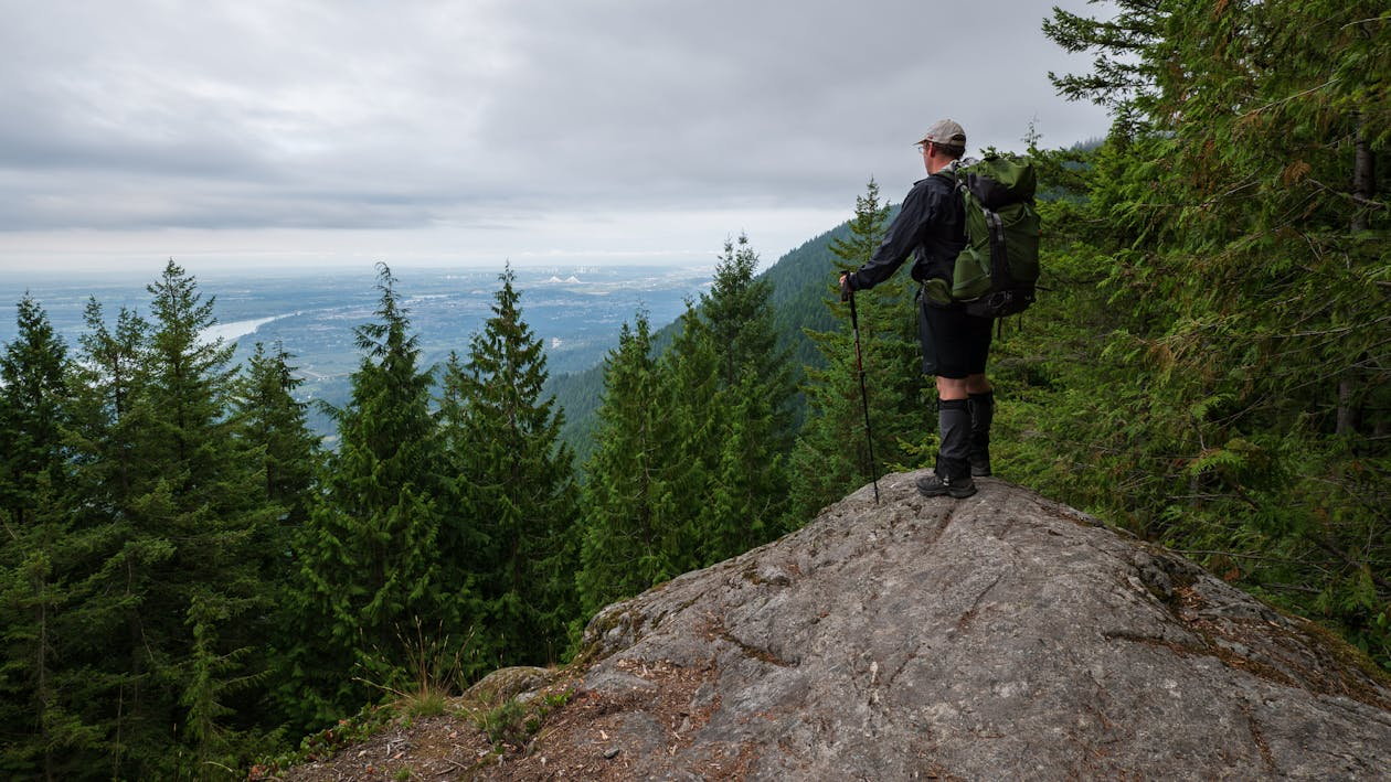 Hiker with a long-distance trekking backpack overlooking a forested mountain trail in the Pacific Northwest.