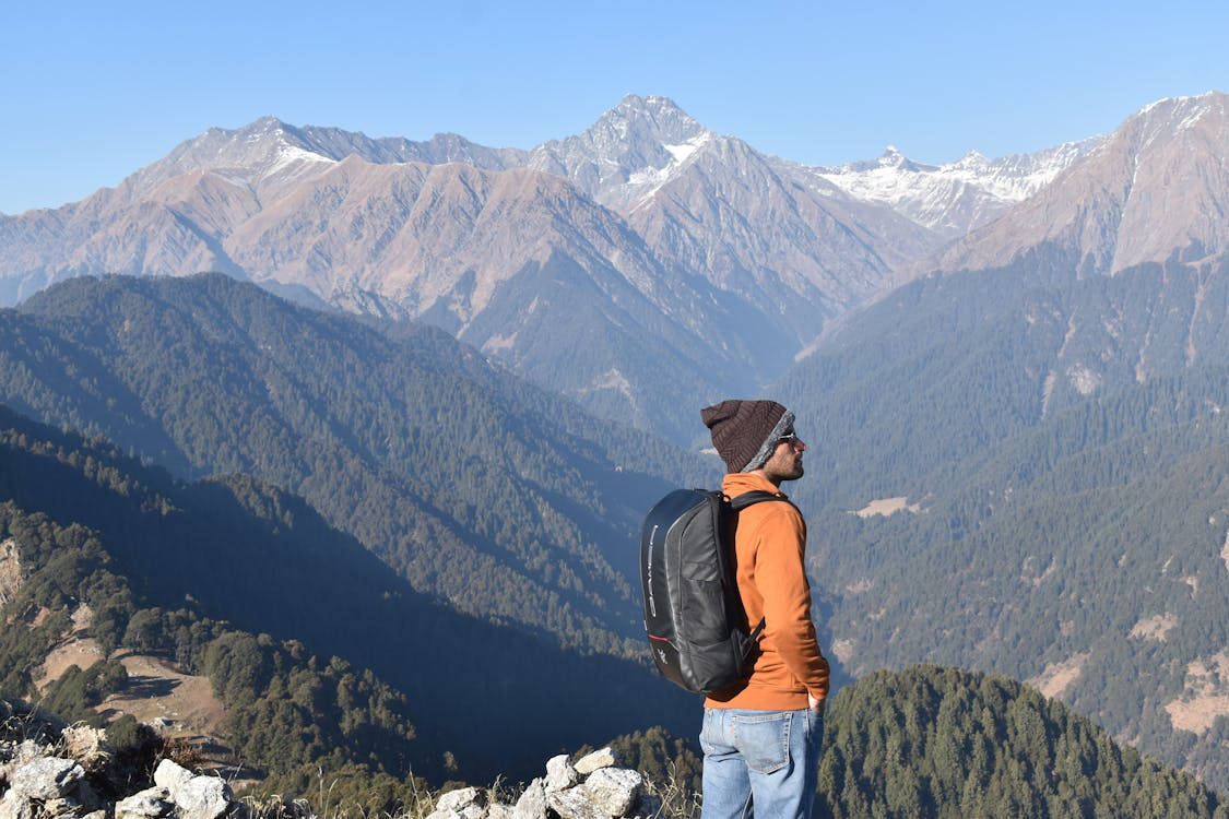 Hiker wearing a mid-volume backpack while overlooking a rugged mountain range