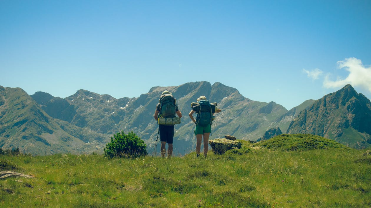 Two hikers with backpacks overlooking a mountain range.