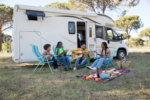 Children and adults sitting on camping chairs outside a van